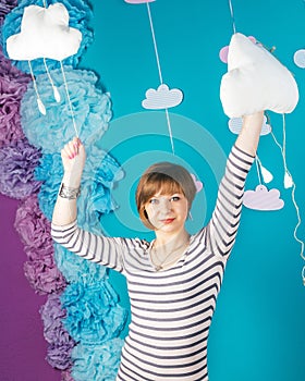 Beautiful lovely young caucasian girl holding soft clouds on blue background.