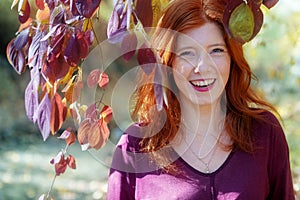 Beautiful lovely young foxy fiery red-haired girl, under violet lilac autumn bush, in the park, happy, cheerful,