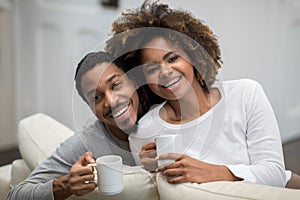 Beautiful loving black spouses drinking coffe at home