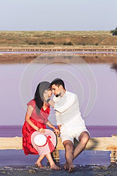 Beautiful loving couple hugging on the background of pink salty lake.