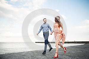 Beautiful loving couple, pride with long dress walking on pier