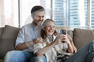 Beautiful loving couple relaxing on sofa with cellphone