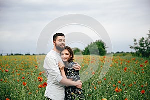 Beautiful loving couple resting on poppies field background