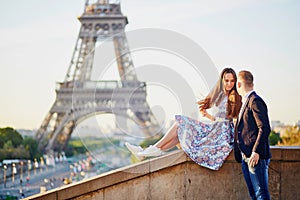 Beautiful loving couple sitting near the Eiffel tower in Paris