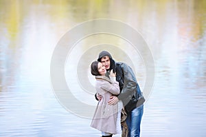 Beautiful loving couple standing by the autumn lake outdoors