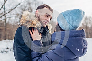 Beautiful loving couple walking and hugging in winter forest. People chilling outdoors