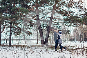 Beautiful loving couple walking in winter forest together. People hugging outdoors