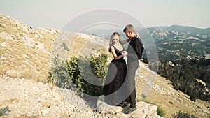 Beautiful loving couple young woman model in a smart long dress and a man in a black suit posing on the camera against a