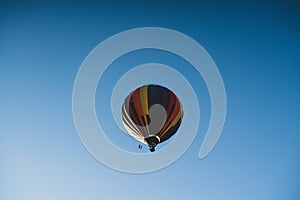 Beautiful low angle shot of a colorful hot air balloon floating in a clear blue sunny sky