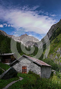 Beautiful lush mountain valley with old cottages and high alpine peaks behind