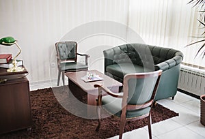 Beautiful luxurious and contemporary green leather sofa with chairs and a table in the office