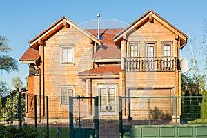 Beautiful luxury big wooden house. Timber cottage villa with with green lawn, garden and blue sky on background