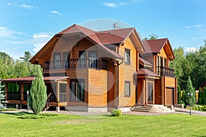 Beautiful luxury big wooden house. Timber cottage villa with with green lawn, garden and blue sky on background