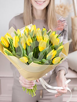 Beautiful luxury bouquet of yellow tulips flowers in woman hand. the work of the florist at a flower shop. cute lovely