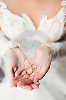 Beautiful luxury bride in elegant white dress holds wedding rings in the hands