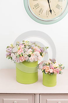 Beautiful luxury bunch of mixed flowers on pink table. the work of the florist at a flower shop. bouquet in green hatbox