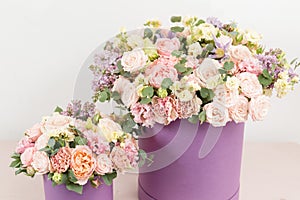 Beautiful luxury bunch of mixed flowers on pink table. the work of the florist at a flower shop. bouquet in lilac hatbox