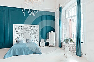 Beautiful luxury classic clean interior bedroom in white and deep blue color with king-size bed and chic carved