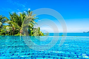 Beautiful luxury outdoor swimming pool in hotel resort with sea ocean around coconut palm tree and white cloud on blue sky