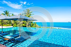 Beautiful luxury outdoor swimming pool in hotel resort with sea ocean around coconut palm tree and white cloud on blue sky