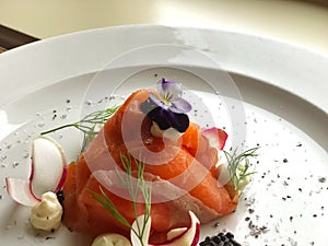 Beautiful luxury plate Appetizer smoked salmon salad with caviar black with drill and edible flower.