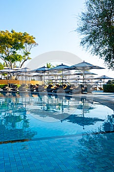 Beautiful luxury umbrella and chair around outdoor swimming pool in hotel and resort with blue sky