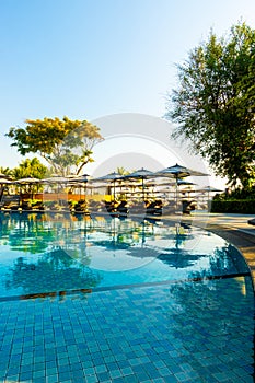 Beautiful luxury umbrella and chair around outdoor swimming pool in hotel and resort with blue sky