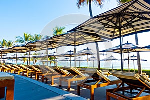 Beautiful luxury umbrella and chair around outdoor swimming pool in hotel and resort with coconut palm tree