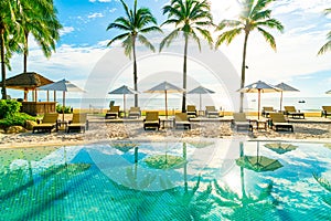 Beautiful luxury umbrella and chair around outdoor swimming pool in hotel and resort with coconut palm tree on blue sky