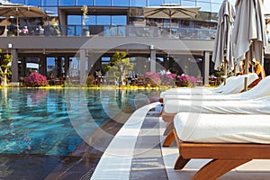 Beautiful luxury umbrella and chair around outdoor swimming pool in hotel and resort with coconut palm tree on blue sky