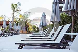 Beautiful luxury umbrella and chair around outdoor swimming pool in hotel and resort with coconut palm tree on blue sky