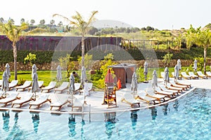 Beautiful luxury umbrella and chair around outdoor swimming pool in hotel and resort with coconut palm tree on blue sky