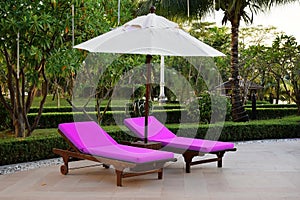 Beautiful luxury umbrella and chair around outdoor swimming pool in hotel and resort with coconut palm tree on blue sky. Luxurious