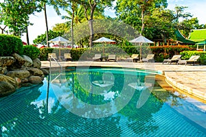 Beautiful luxury umbrella and chair around outdoor swimming pool in hotel and resort with coconut palm tree on sunset  or sunrise