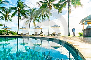 Beautiful luxury umbrella and chair around outdoor swimming pool in hotel and resort with coconut palm tree on sunset  or sunrise