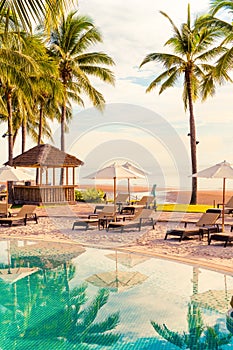 Beautiful luxury umbrella and chair around outdoor swimming pool in hotel and resort with coconut palm tree on sunset  or sunrise