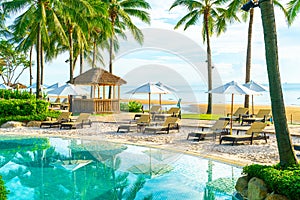 Beautiful luxury umbrella and chair around outdoor swimming pool in hotel and resort with coconut palm tree on sunset  or sunrise