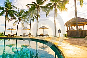 Beautiful luxury umbrella and chair around outdoor swimming pool in hotel and resort with coconut palm tree on sunset  or sunrise