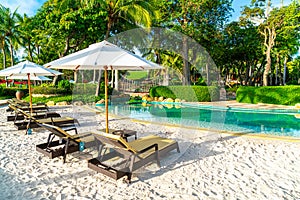 Beautiful luxury umbrella and chair around outdoor swimming pool in hotel and resort with coconut palm tree on sunset  or sunrise