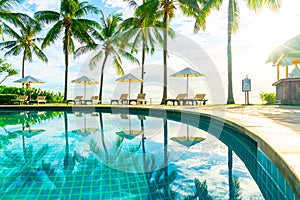 Beautiful luxury umbrella and chair around outdoor swimming pool in hotel and resort with coconut palm tree on sunset  or sunrise