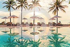 Beautiful luxury umbrella and chair around outdoor swimming pool in hotel and resort with coconut palm tree on sunset  or sunrise