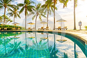 Beautiful luxury umbrella and chair around outdoor swimming pool in hotel and resort with coconut palm tree on sunset  or sunrise