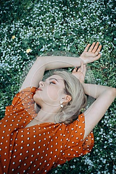 Beautiful lying woman enjoying daisy field, pretty girl relaxing outdoor. Close-up