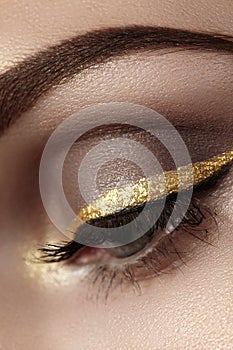 Beautiful macro shot of female eye with ceremonial makeup. Perfect shape of eyebrows, eyeliner and pretty gold line on eyelid