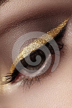 Beautiful macro shot of female eye with ceremonial makeup. Perfect shape of eyebrows, eyeliner and pretty gold line on eyelid