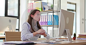 Beautiful mad businesswoman is sitting at workplace in office and looking at computer with angry expression on face