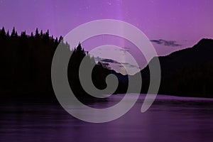 Beautiful magenta aurora borealis and pillar of light reflected in river in the Jacques-Cartier National Park