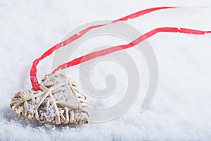 Beautiful magical vintage beige heart tied with a red ribbon on a white snow background. Winter and Christmas concept