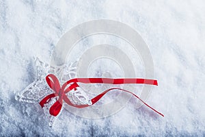 Beautiful magical vintage white star tied with a red ribbon on a white snow background. Winter and Christmas concept.