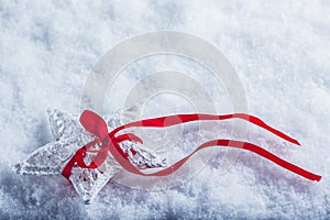 Beautiful magical vintage white star tied with a red ribbon on a white snow background. Winter and Christmas concept.